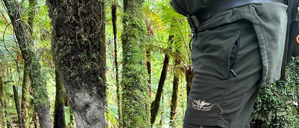 Person wearing green hunting shorts with Game Gear Logo in a forest setting